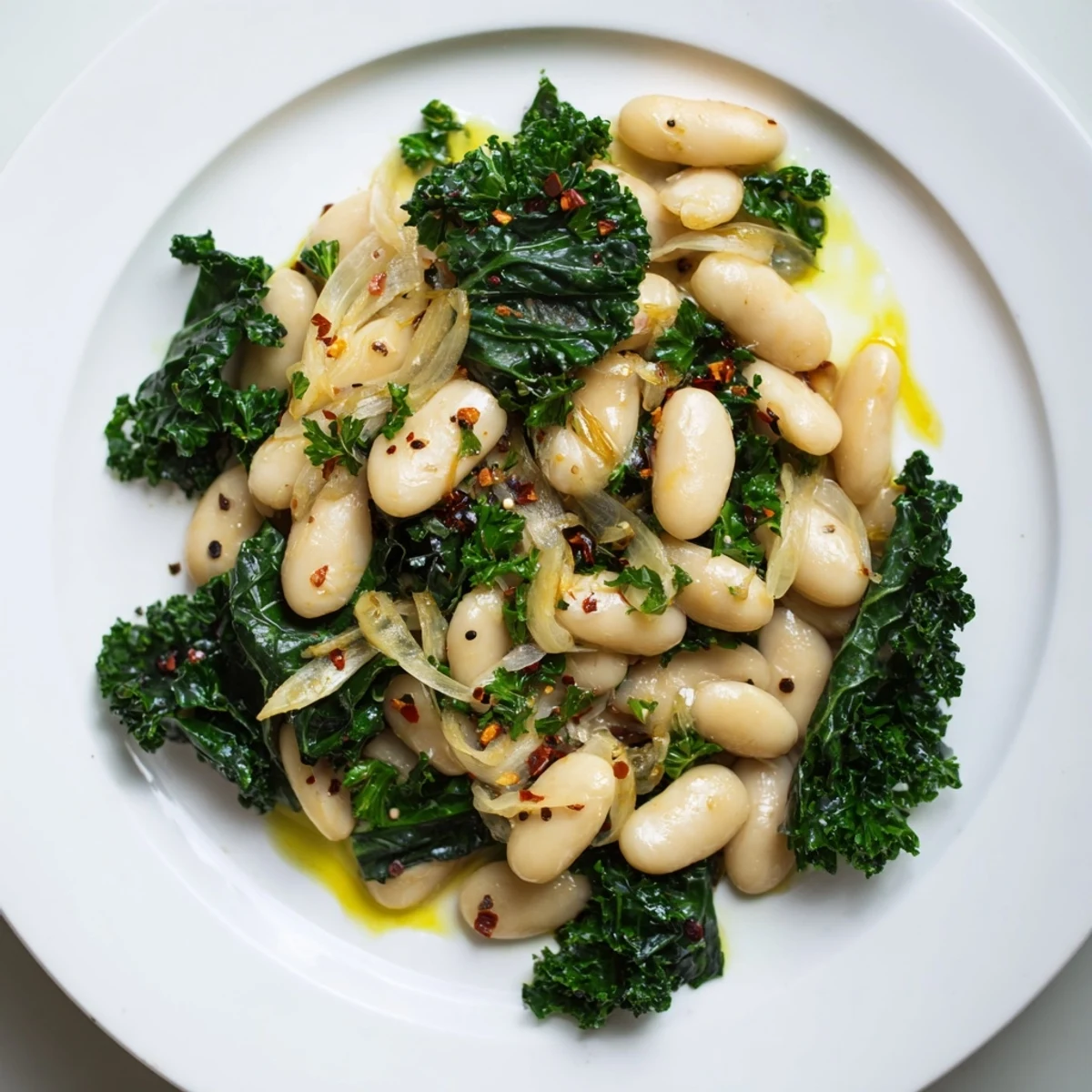 A bowl of vibrant garlicky beans with winter greens, drizzled with olive oil, ready to eat.
