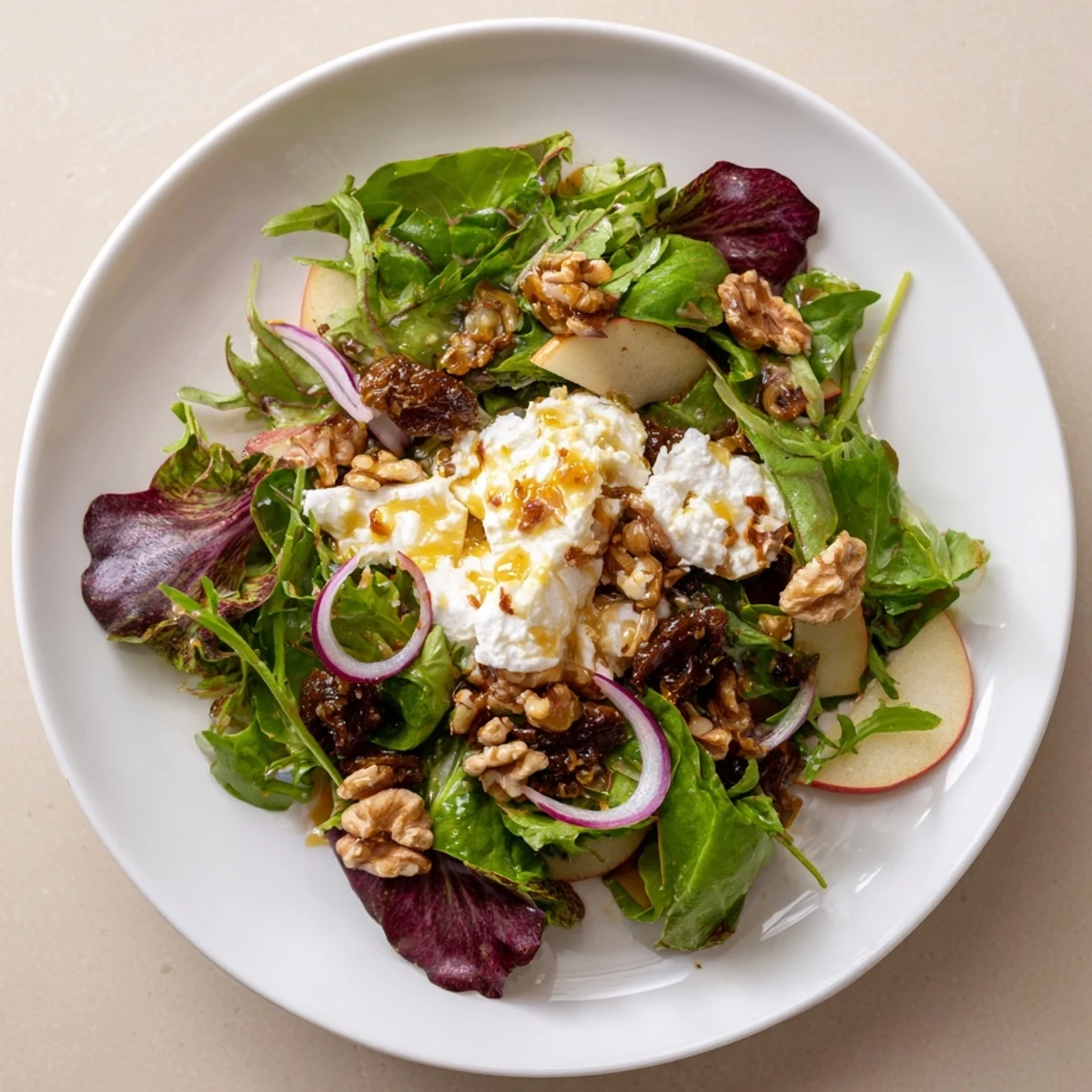 Spiced Honey and Date Goat Cheese Salad displays crisp greens, creamy goat cheese, and chopped dates, drizzled with warm, spiced honey.