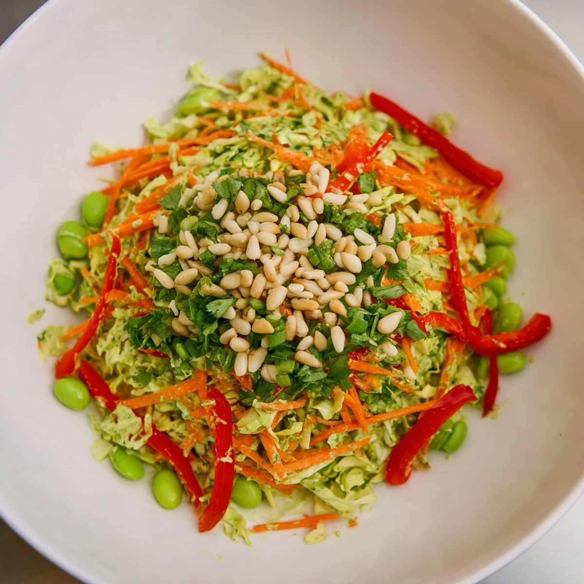 A big bowl of refreshing Crunchy Cabbage and Edamame Salad, featuring crisp vegetables and vibrant green dressing.