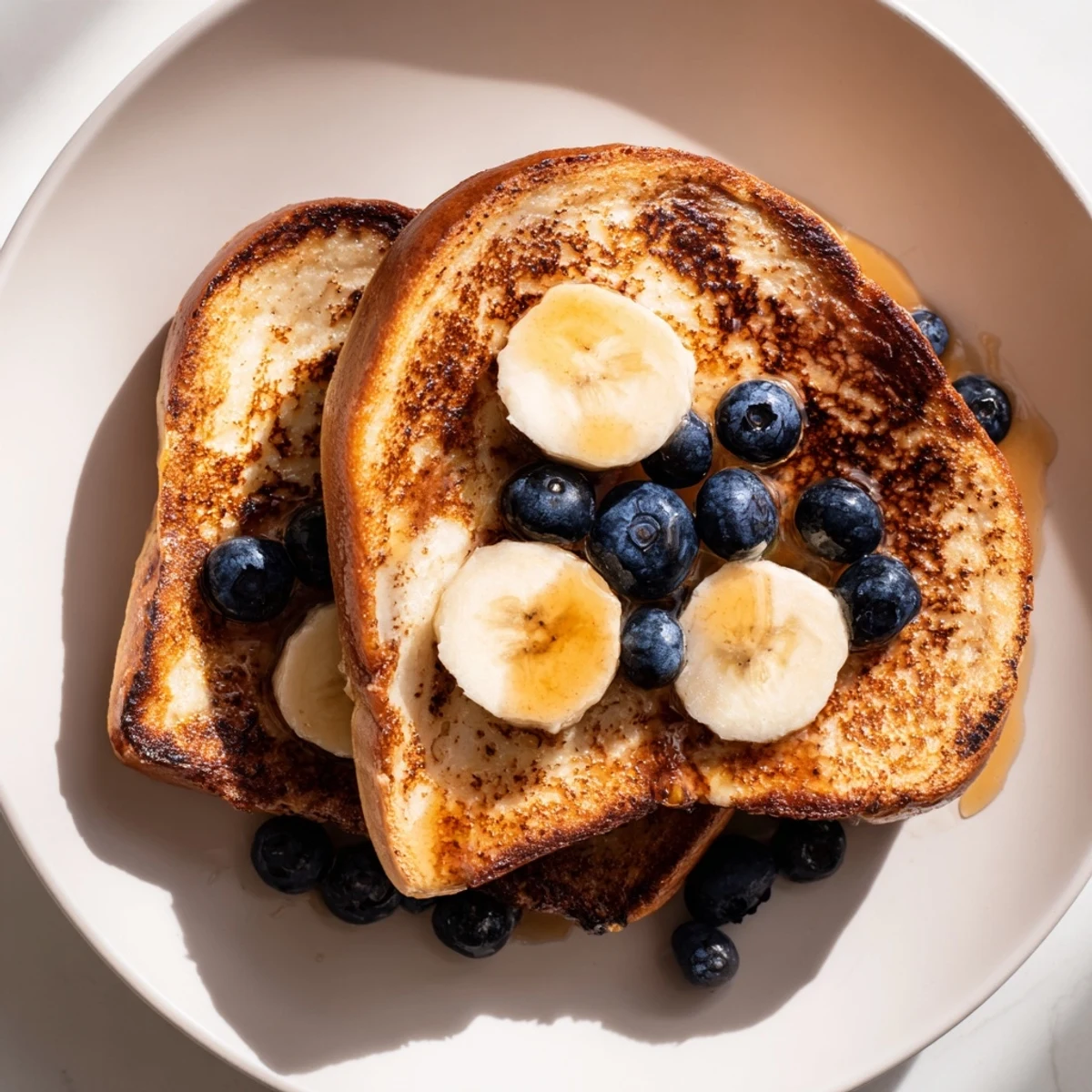 Golden, thick slices of Protein French Toast, drizzled with maple syrup and fresh berries.
