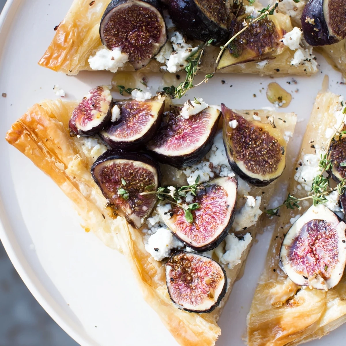 Golden-brown puff pastry truffle pizza, with figs, goat cheese, and a honey drizzle ready to eat!