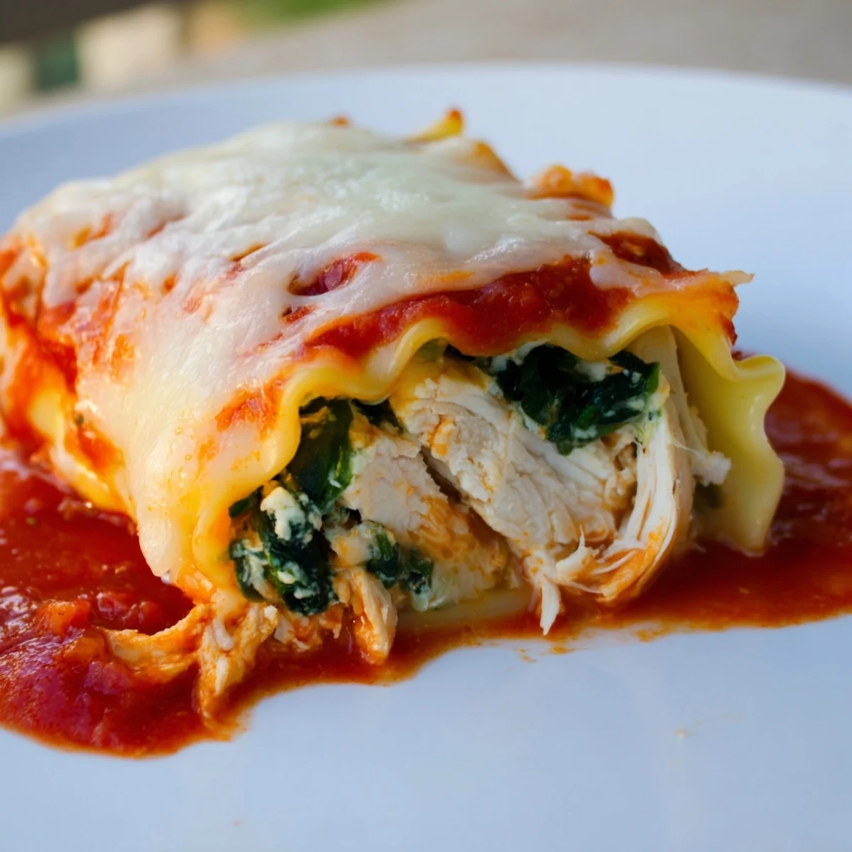 Chicken and Spinach Lasagna Rolls rest in a baking dish, ready to serve with a side salad and garlic bread.