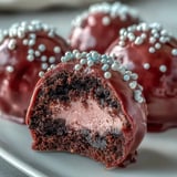 Close-up of a smooth Oreo Truffle Ball with Pink Candy Coating, revealing a rich cream cheese core.