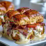 Golden brioche sliders layered with roast turkey, crispy bacon, and creamy Mornay sauce for a Kentucky Derby party treat.