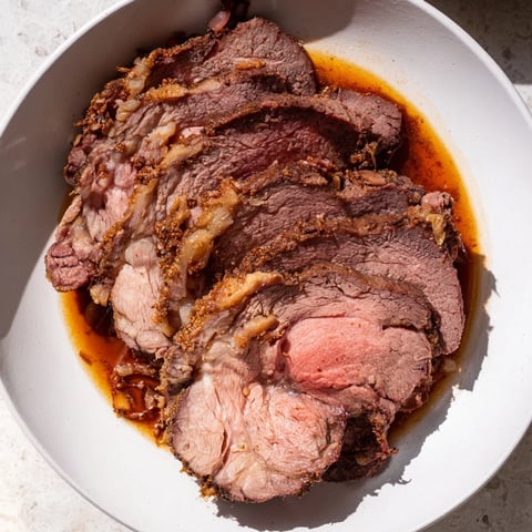 Fork-tender Budget Holiday Chuck Roast, slow-cooked to perfection, resting in savory, rich pan juices.