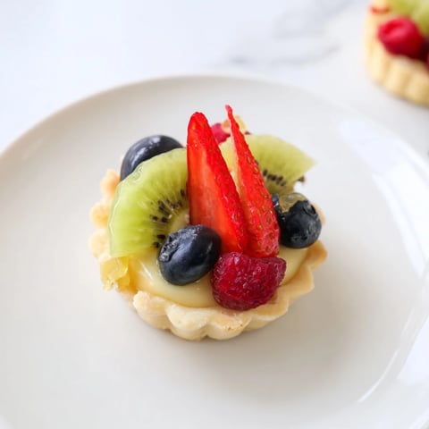 Golden, flaky mini fruit tartlets showcasing a beautiful fruit circle, perfect for a special occasion.