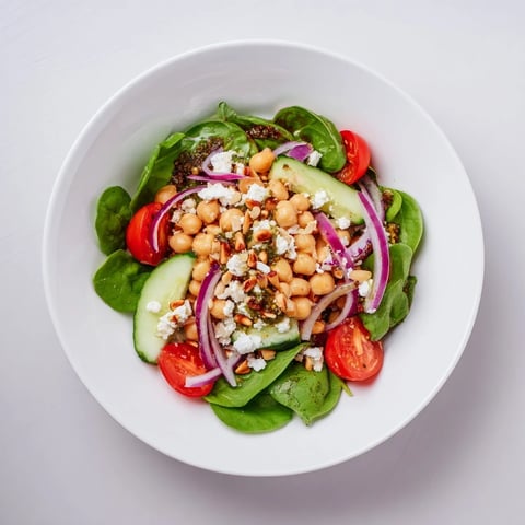 Vibrant Pesto Chickpea and Spinach Salad with juicy tomatoes, drizzled with homemade pesto for a light dinner.