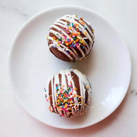 Six glossy, handmade hot chocolate bombs filled with cocoa powder and mini marshmallows, ready to be melted into steaming milk for a cozy treat.  