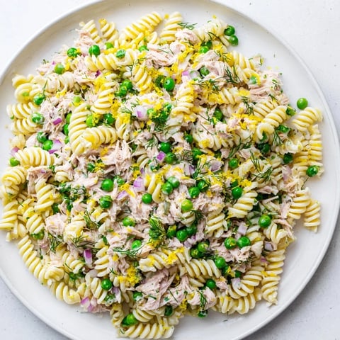 A vibrant bowl of Lemony Tuna Pasta Salad with tender fusilli, flaked tuna, bright green peas, and fresh herbs tossed in a zesty lemon vinaigrette.  