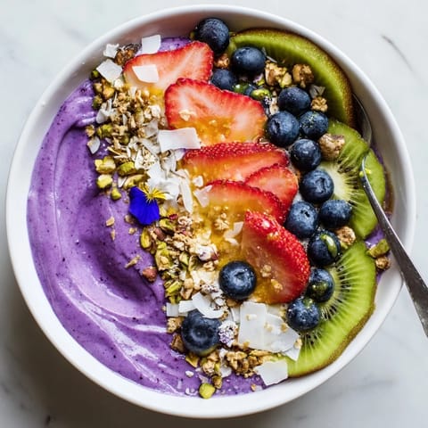 Colorful breakfast smoothie bowl featuring purple yam and fresh berry toppings.  