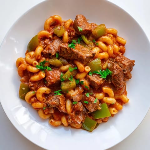 Close-up of savory goulash, highlighting tender beef and pasta in a rich, tomato-based sauce.