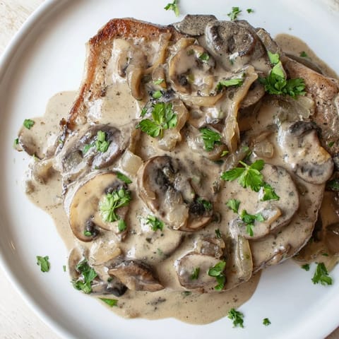 Tender Stove Top Pork Chops, nestled in a rich mushroom cream sauce, perfect for a cozy supper.