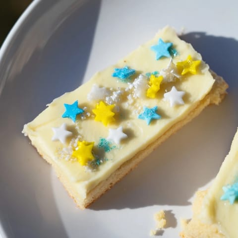Golden-baked Twinkle Twinkle Star Dessert Bars, beautifully frosted with vanilla and topped with colorful star sprinkles.