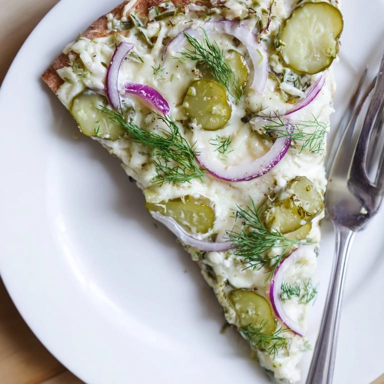 Sliced pickle pizza garnished with fresh dill, ideal for sharing at gatherings.