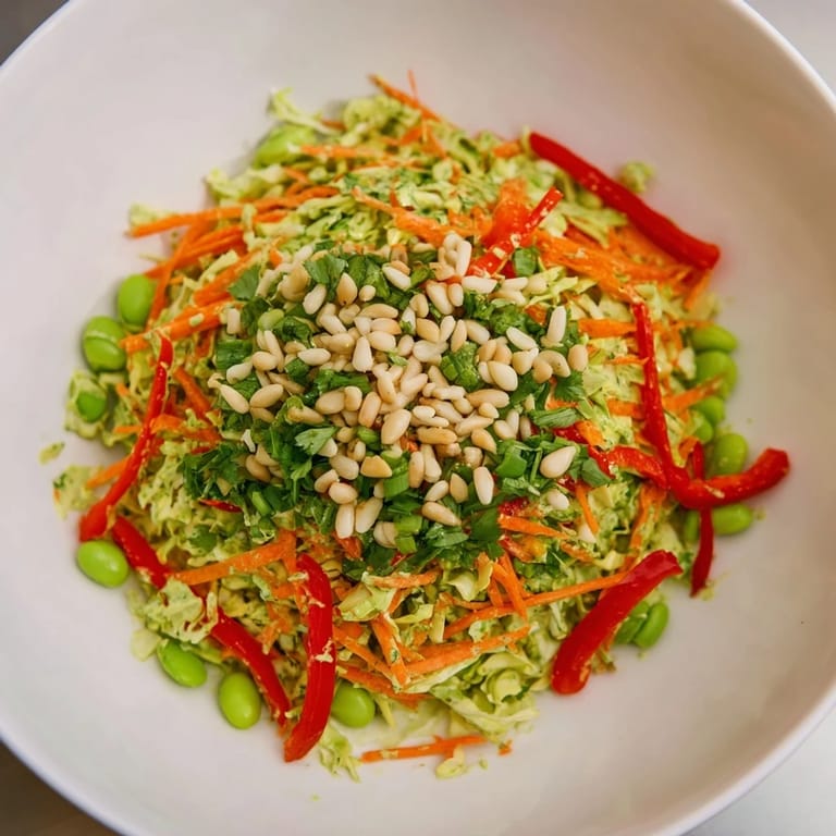 A big bowl of refreshing Crunchy Cabbage and Edamame Salad, featuring crisp vegetables and vibrant green dressing.