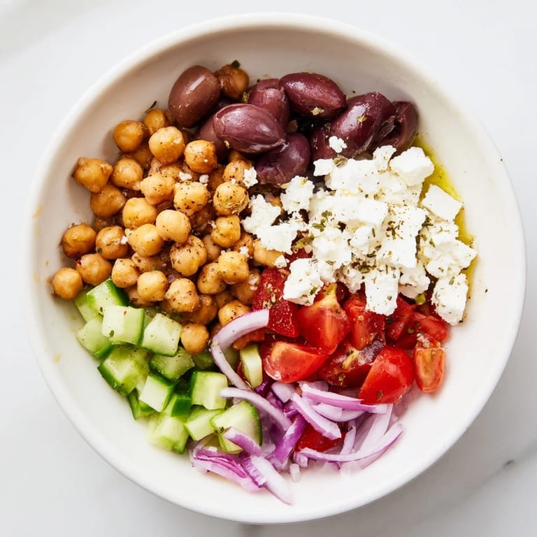 Fresh, plant-based Mediterranean Chickpea and Feta Bowl served, with olives and parsley—yummy, healthy meal option.