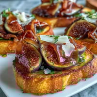Crostini with Prosciutto & Fig: Crispy toasted baguette slices topped with savory prosciutto and sweet fresh figs, garnished with thyme.