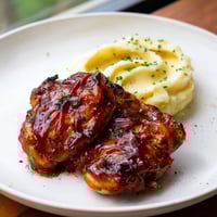 Golden, glistening honey BBQ chicken thighs alongside a mound of creamy garlic mashed potatoes.